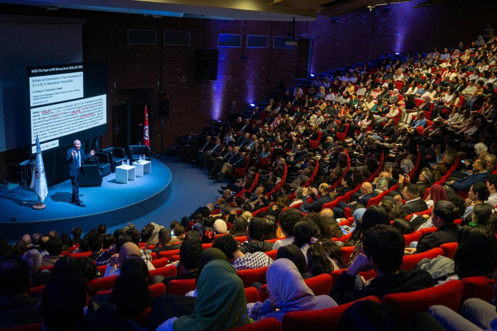Un orateur s'adresse à une large assemblée assise dans un auditorium.